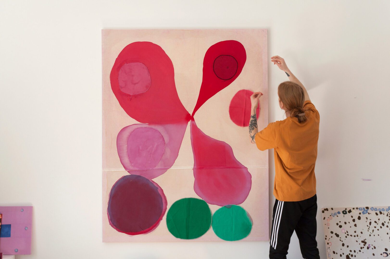 Person hanging abstract colorful painting.