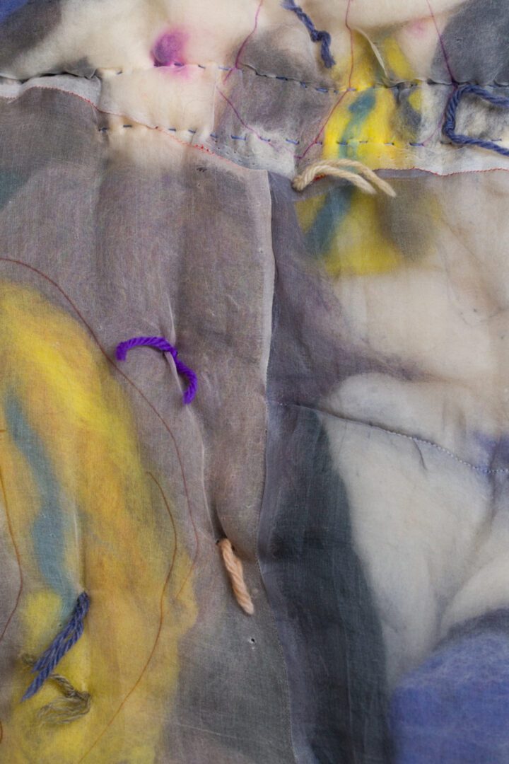 Close-up of fabric with stitching and dye.