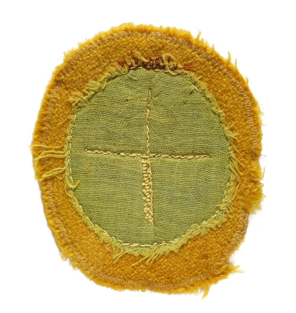 Green fabric patch with yellow border and a cross.