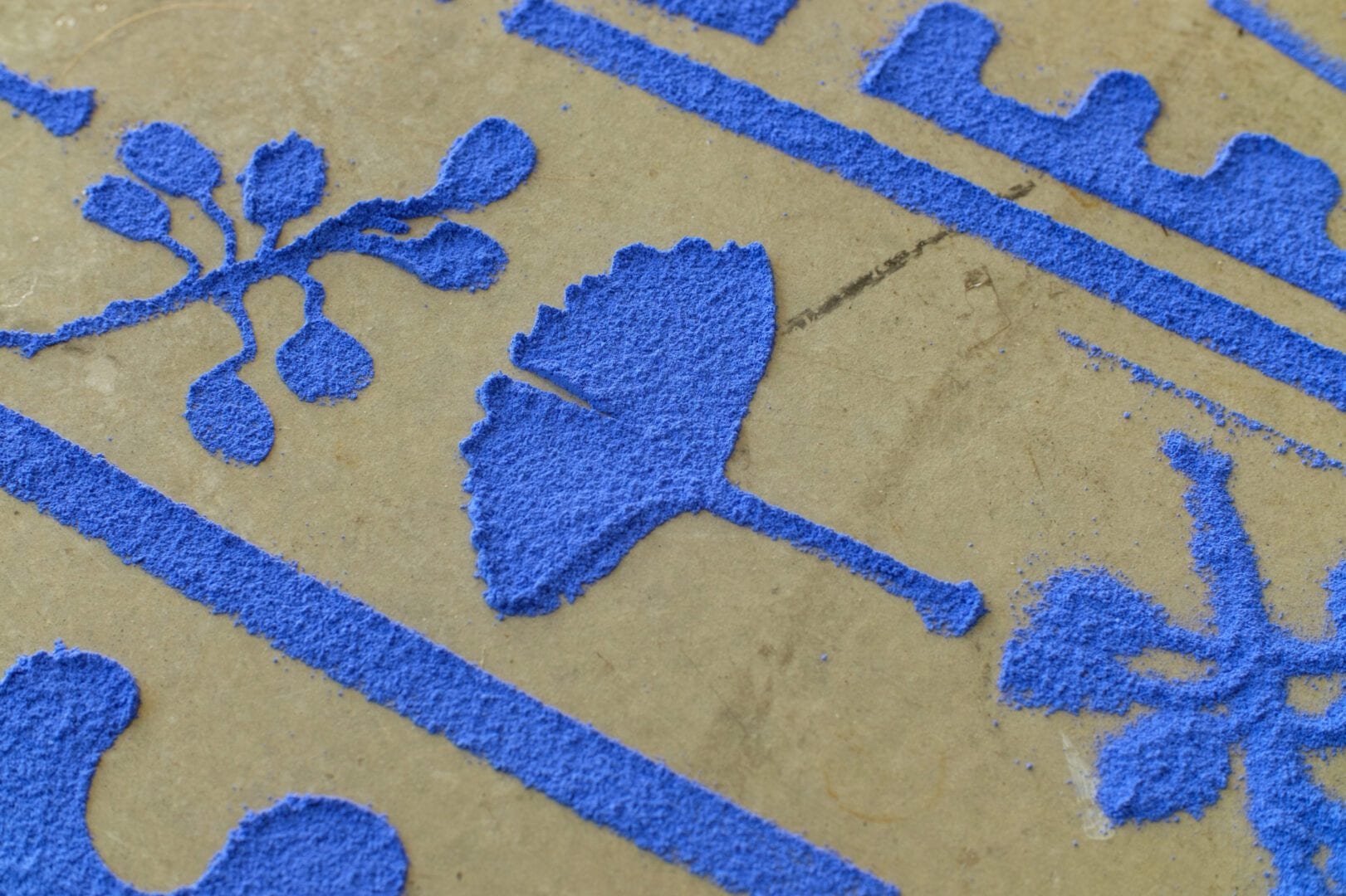 Blue powder drawings on a beige surface.