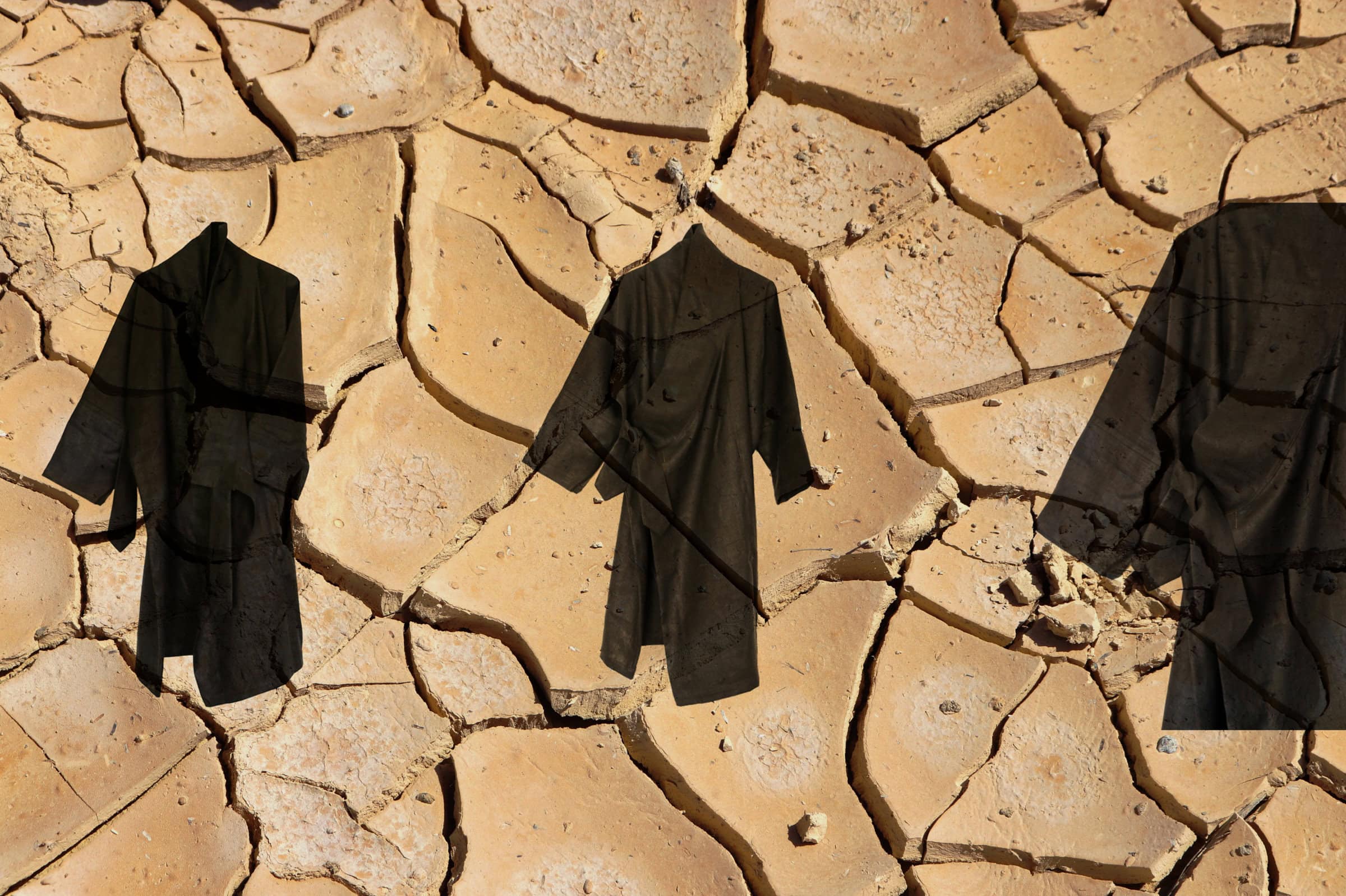 Three black robes on cracked earth.