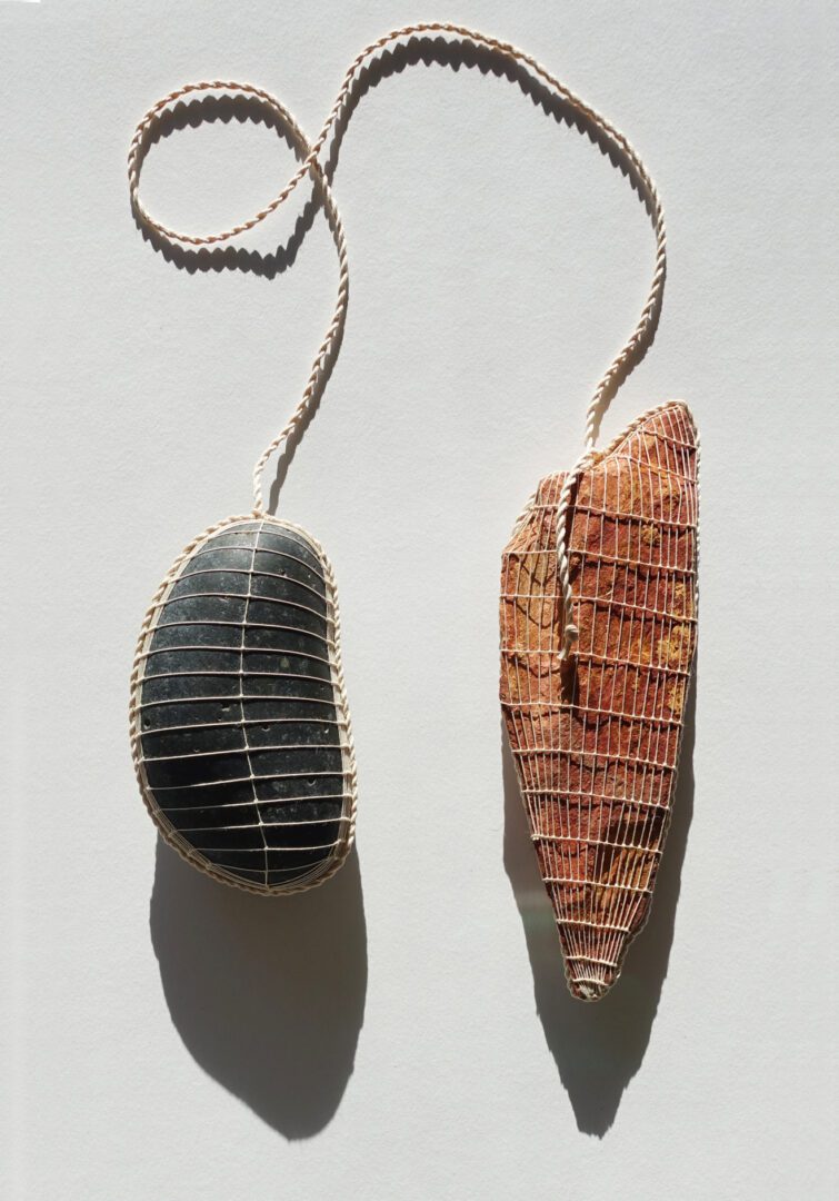 Two stones wrapped in twine on white background.