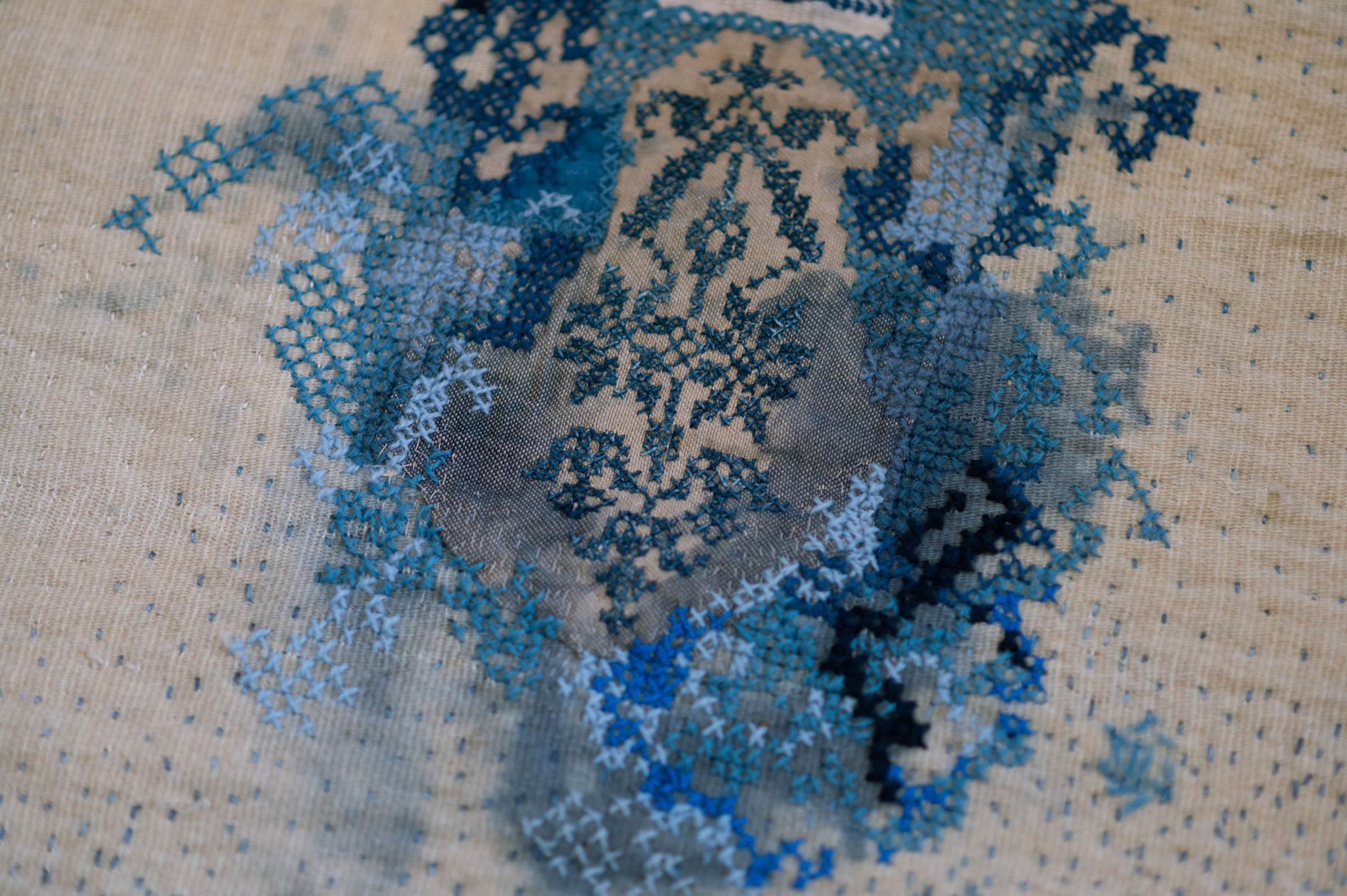 Blue and white cross-stitch design on fabric.