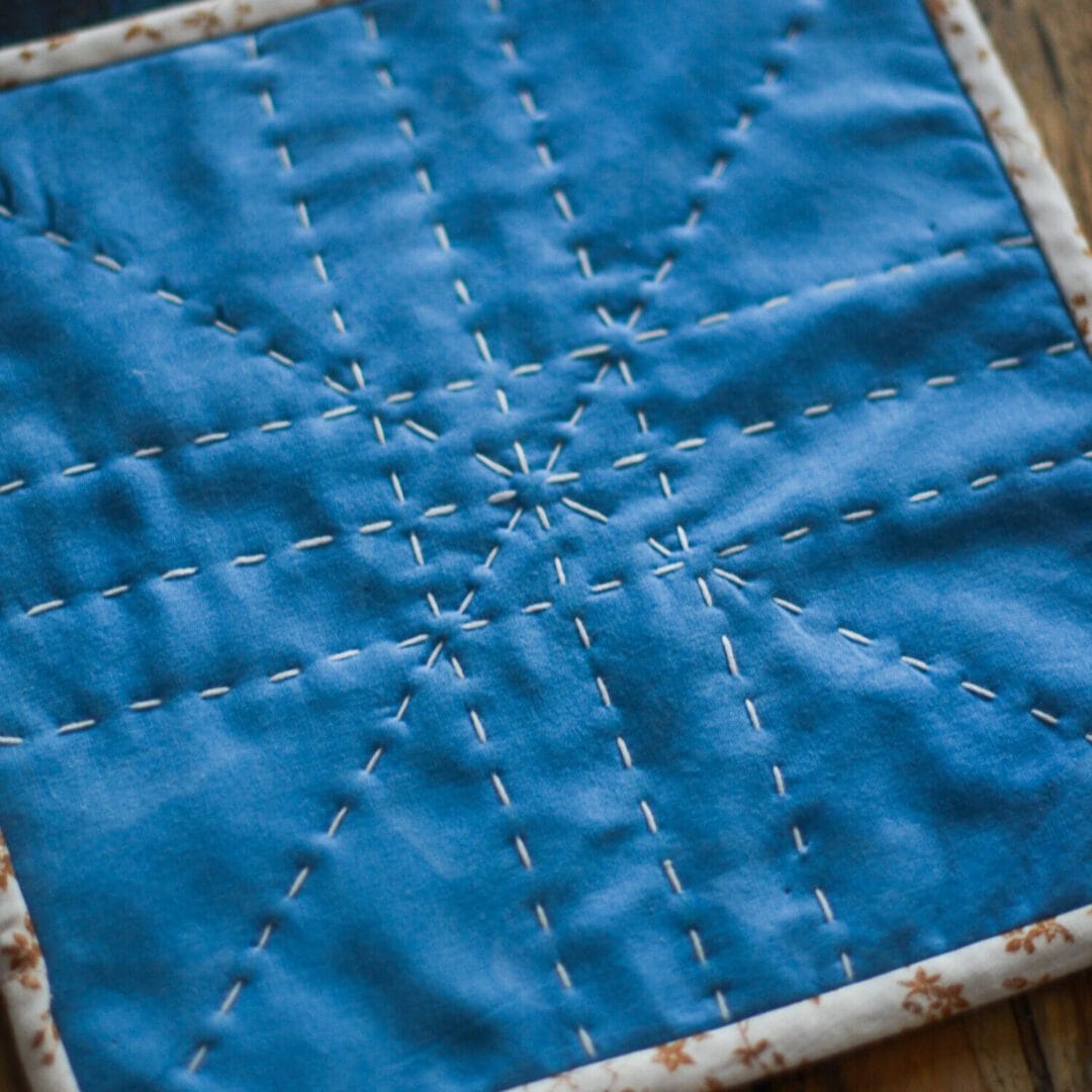 Blue quilted fabric with white stitching.