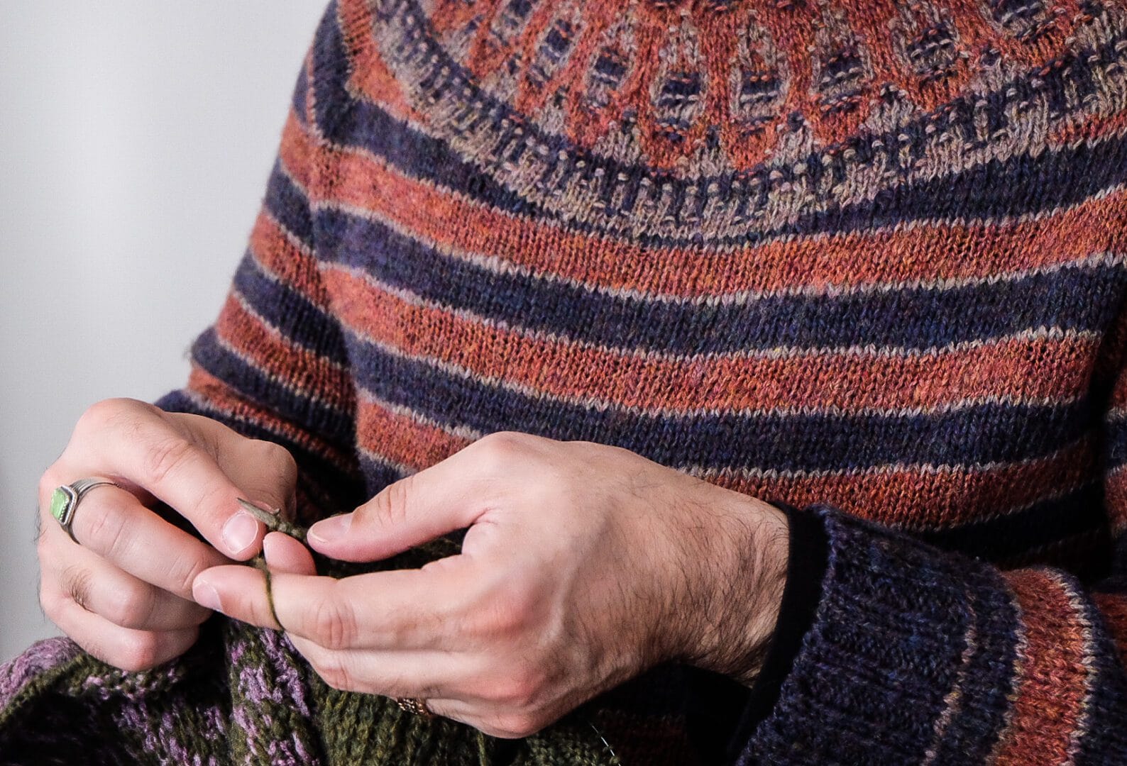 Person knitting with striped sweater.