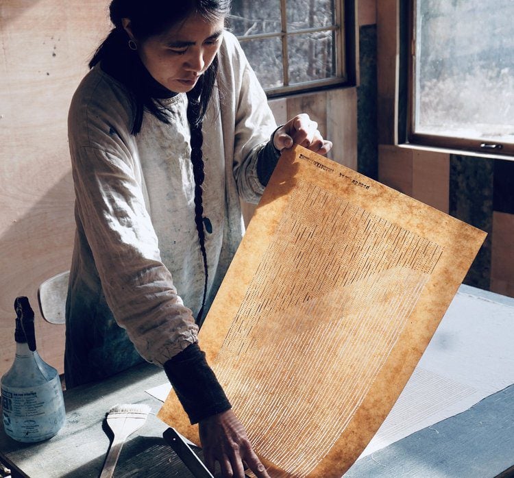 Woman examining a piece of patterned paper.