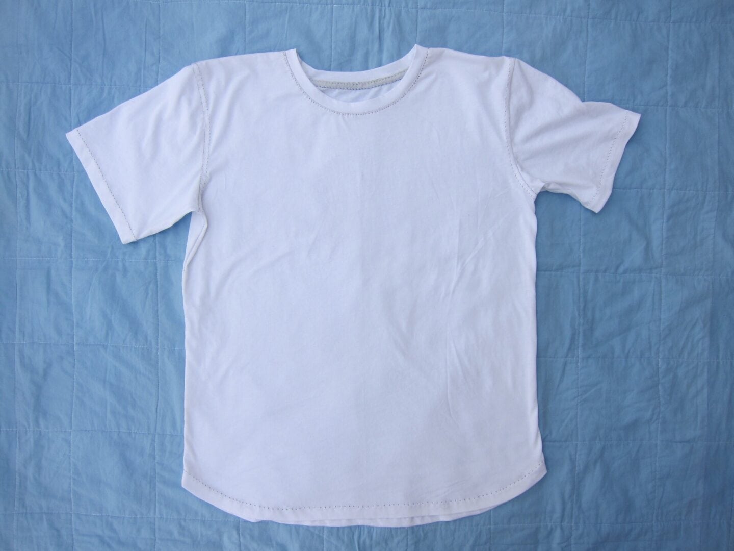 White T-shirt on blue quilted fabric.