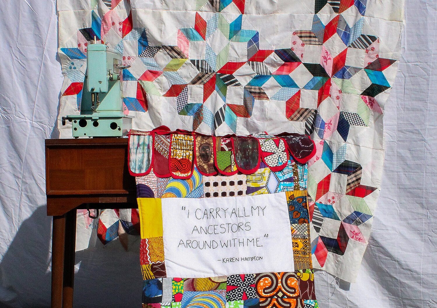 Sewing machine on table with colorful quilt.