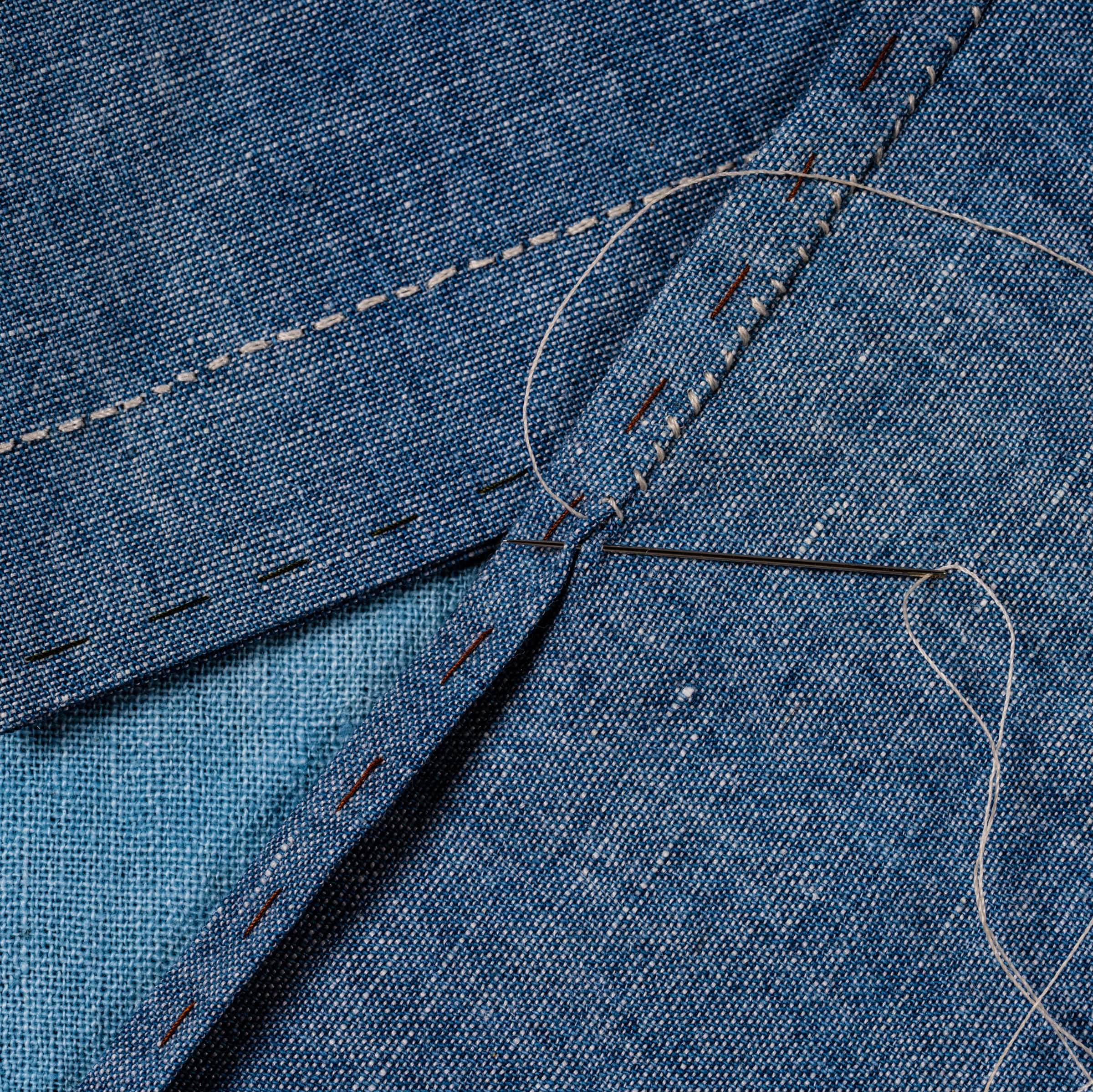 Close up of needle and thread in denim.