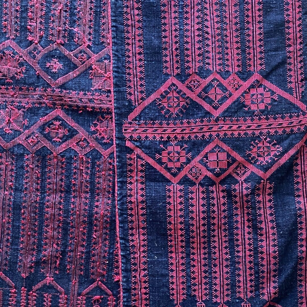 Intricate pink embroidery on blue fabric.