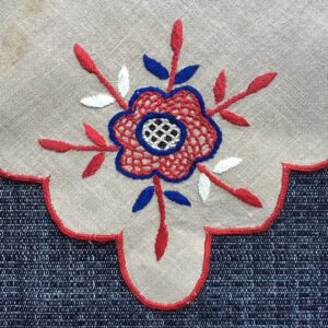 Red and blue embroidered flower on linen.
