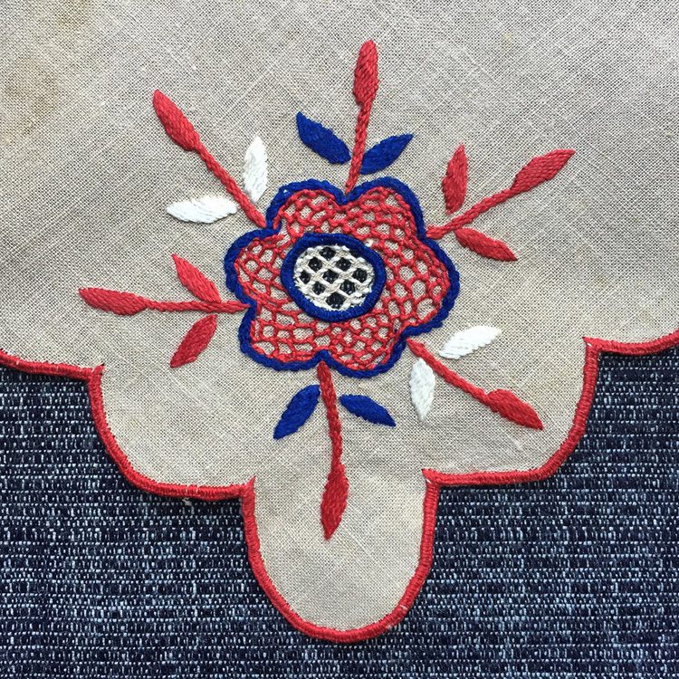 Red and blue embroidered flower on linen.