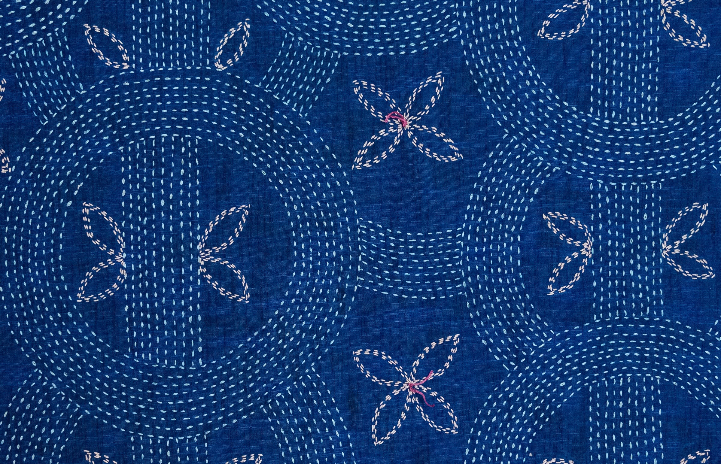 Blue fabric with white and pink embroidery.