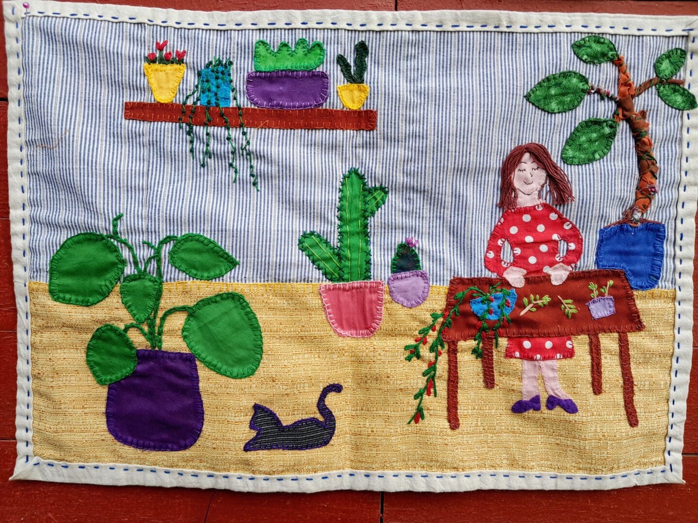 Embroidered textile art of a woman gardening.