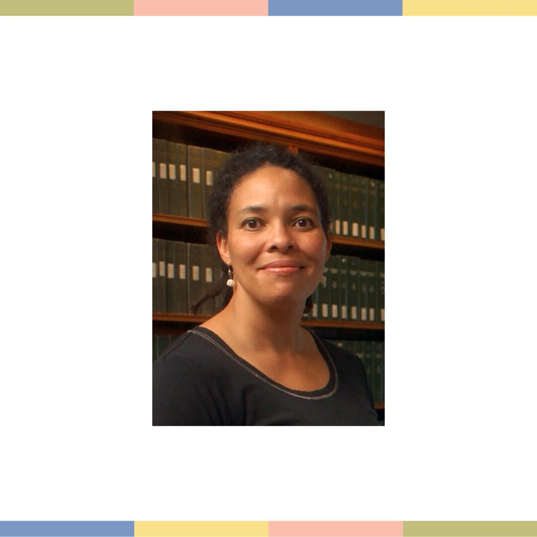 Woman with dark hair in front of bookshelves.