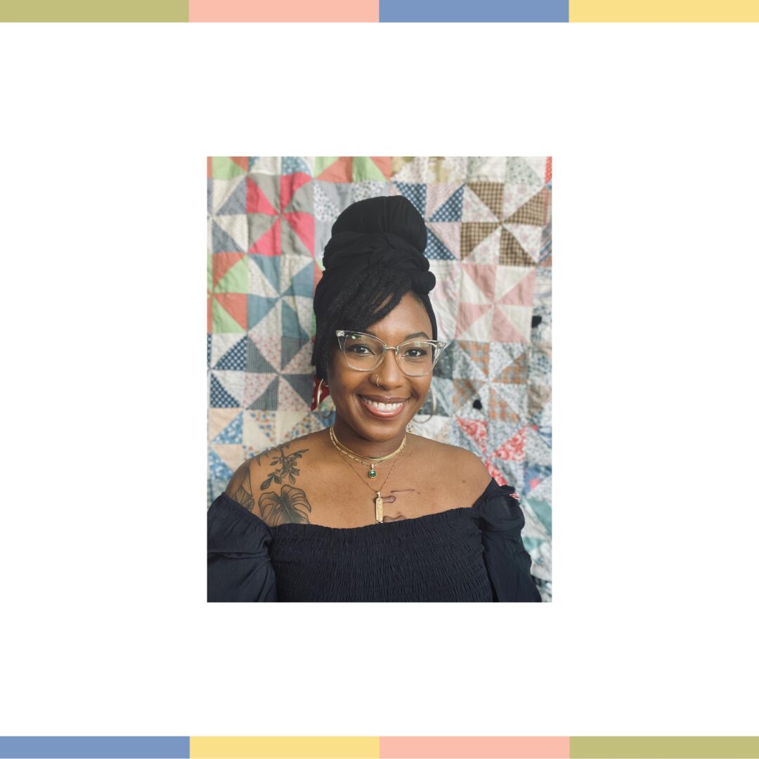 Woman smiling in front of a quilt.