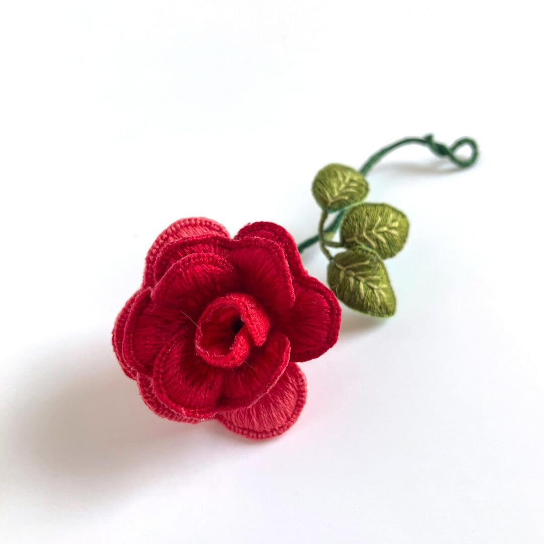 Red fabric rose with green leaves.