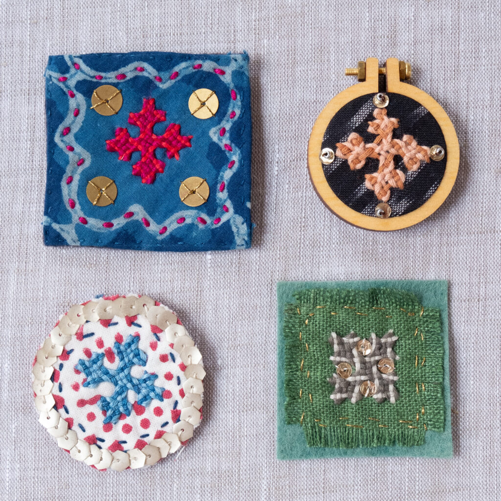 Embroidered fabric squares on linen background.