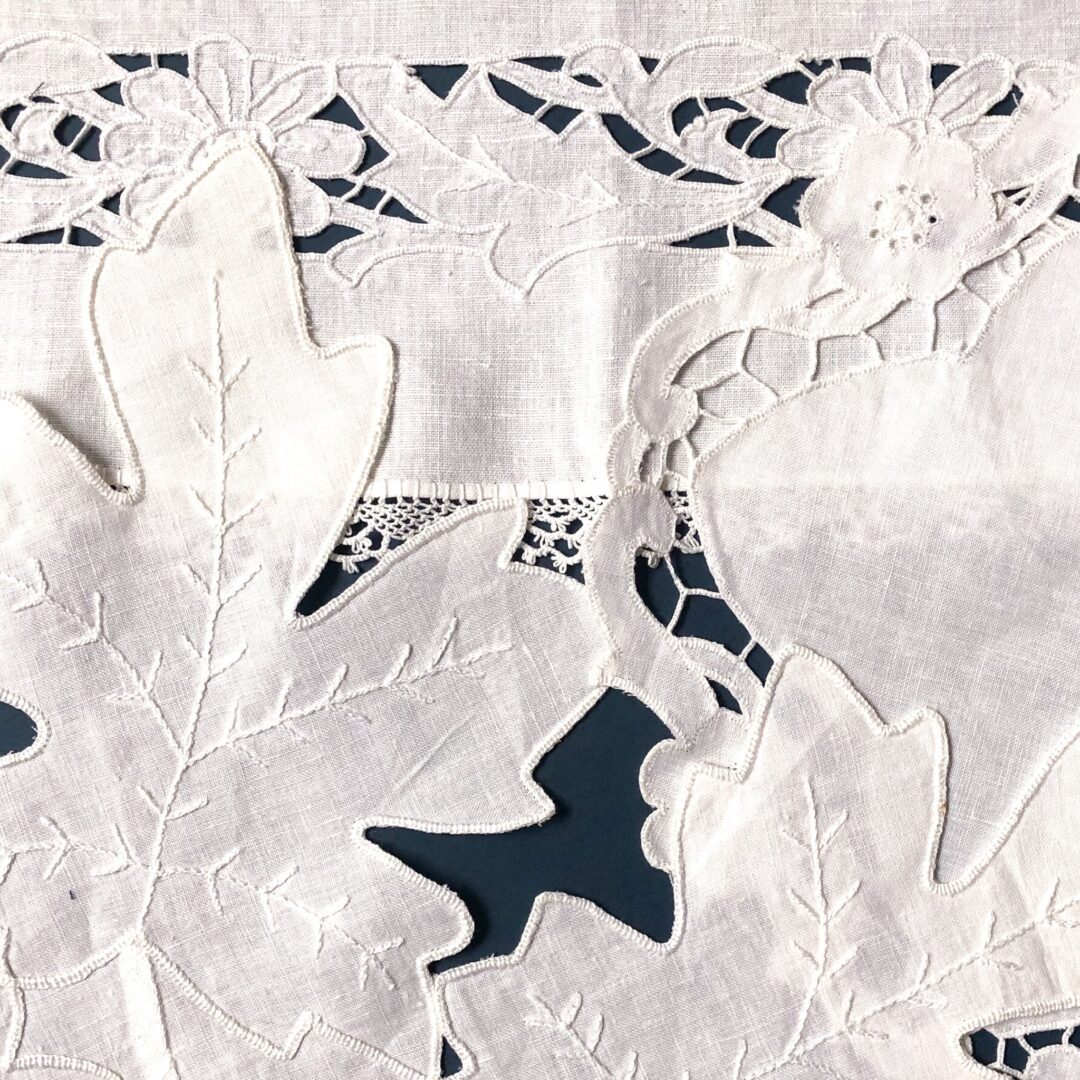 White embroidered fabric with leaf designs.