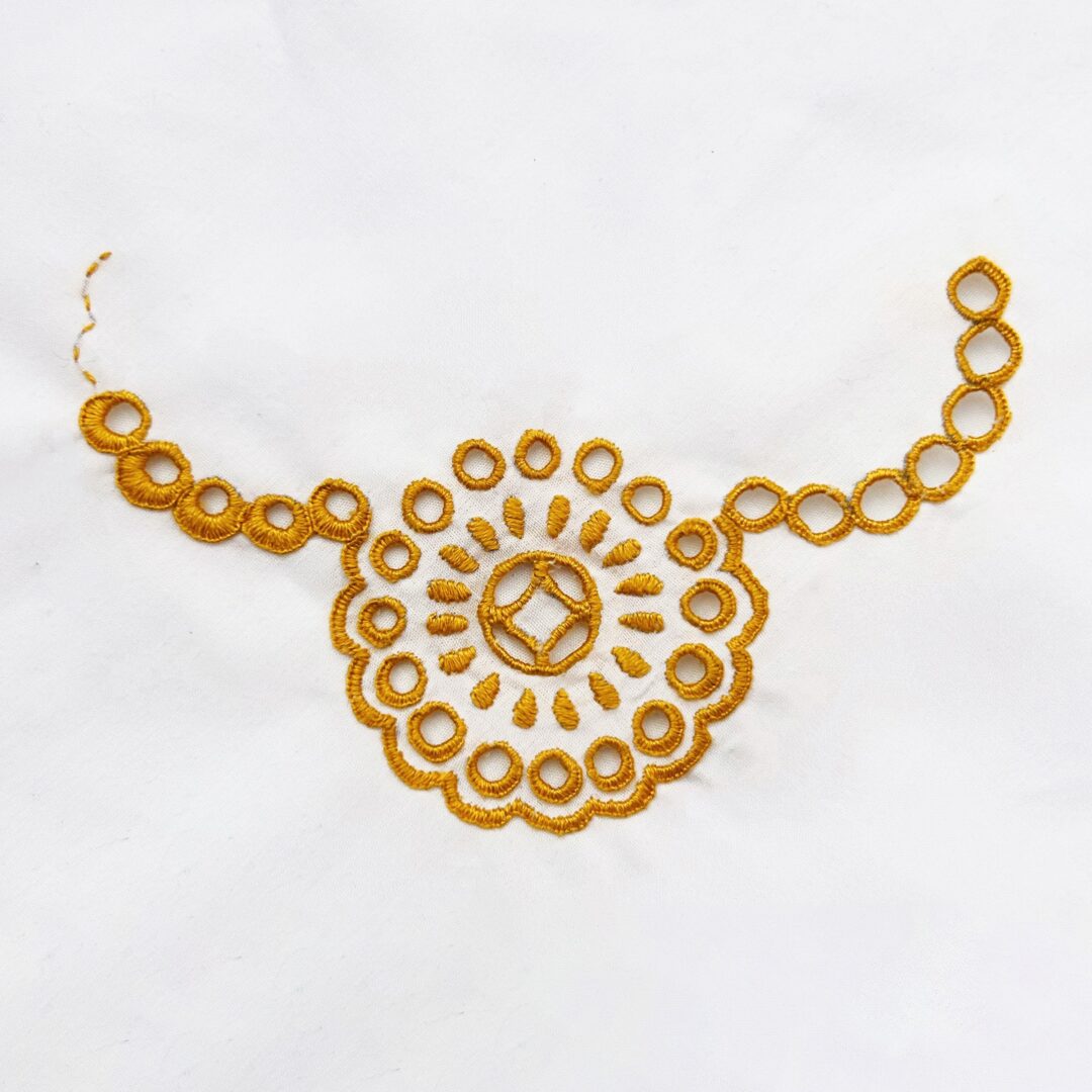 Gold embroidered circles on white fabric.