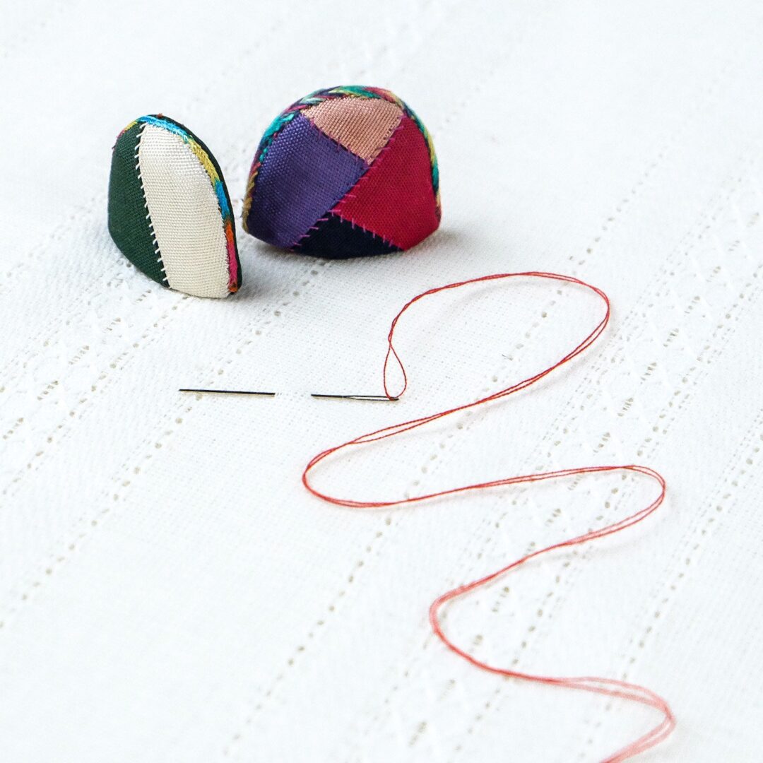 Two fabric balls and red thread.