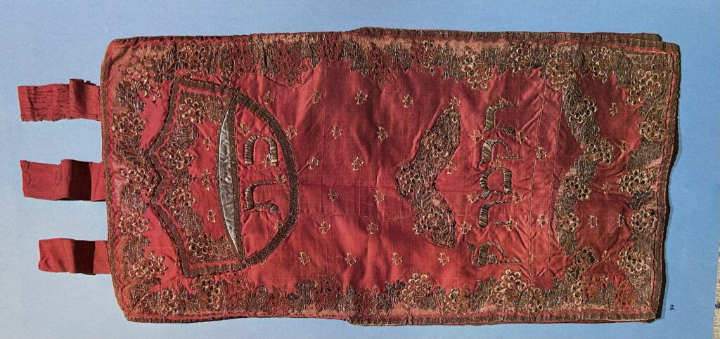 Red fabric with gold and silver embroidery.