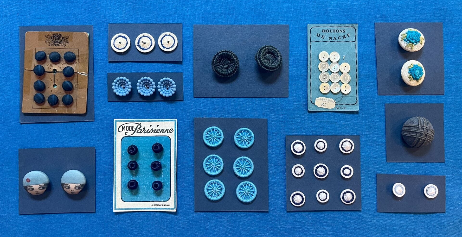 Assortment of vintage buttons on blue fabric.