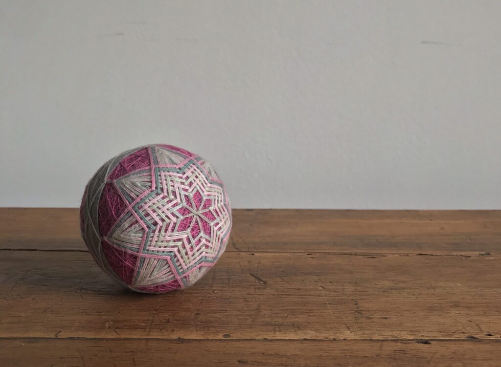 Pink and grey hand-stitched yarn ball.