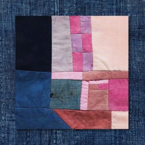 Patchwork quilt with blue, pink, and red fabric.