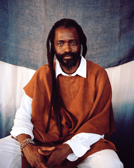 Man with dreadlocks wearing a brown sweater.