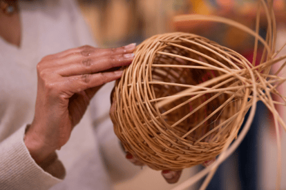 A person weaving a wicker basket.