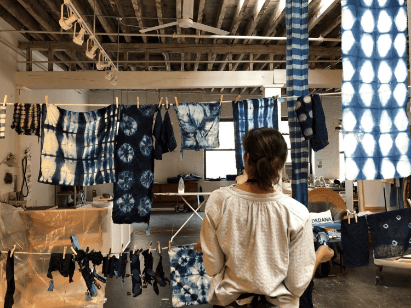 Woman in studio with indigo tie-dye fabric.