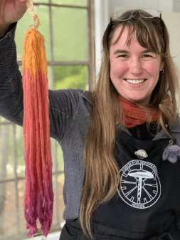 Smiling woman holding a dyed yarn skein.