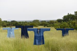 Four blue shirts on scarecrows in field.