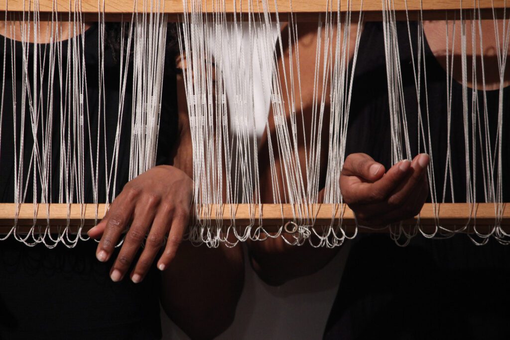 Hands trapped in a loom with string.