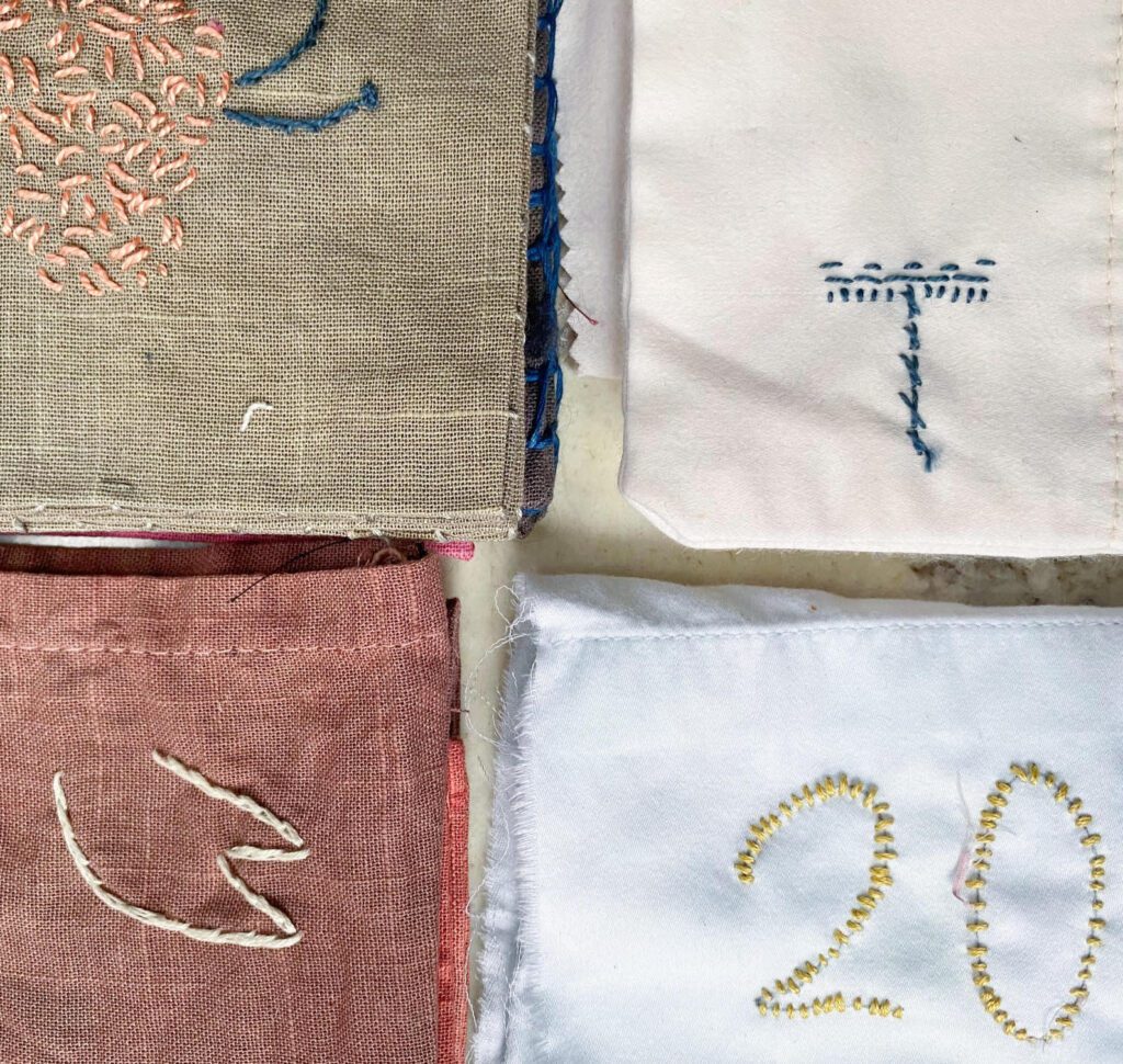 Embroidered fabric squares with numbers and designs.