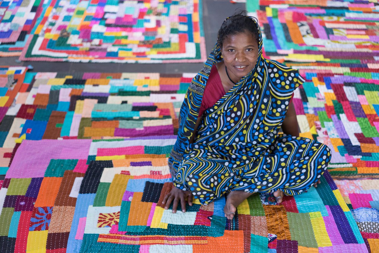 Woman sitting on colorful patchwork quilt.