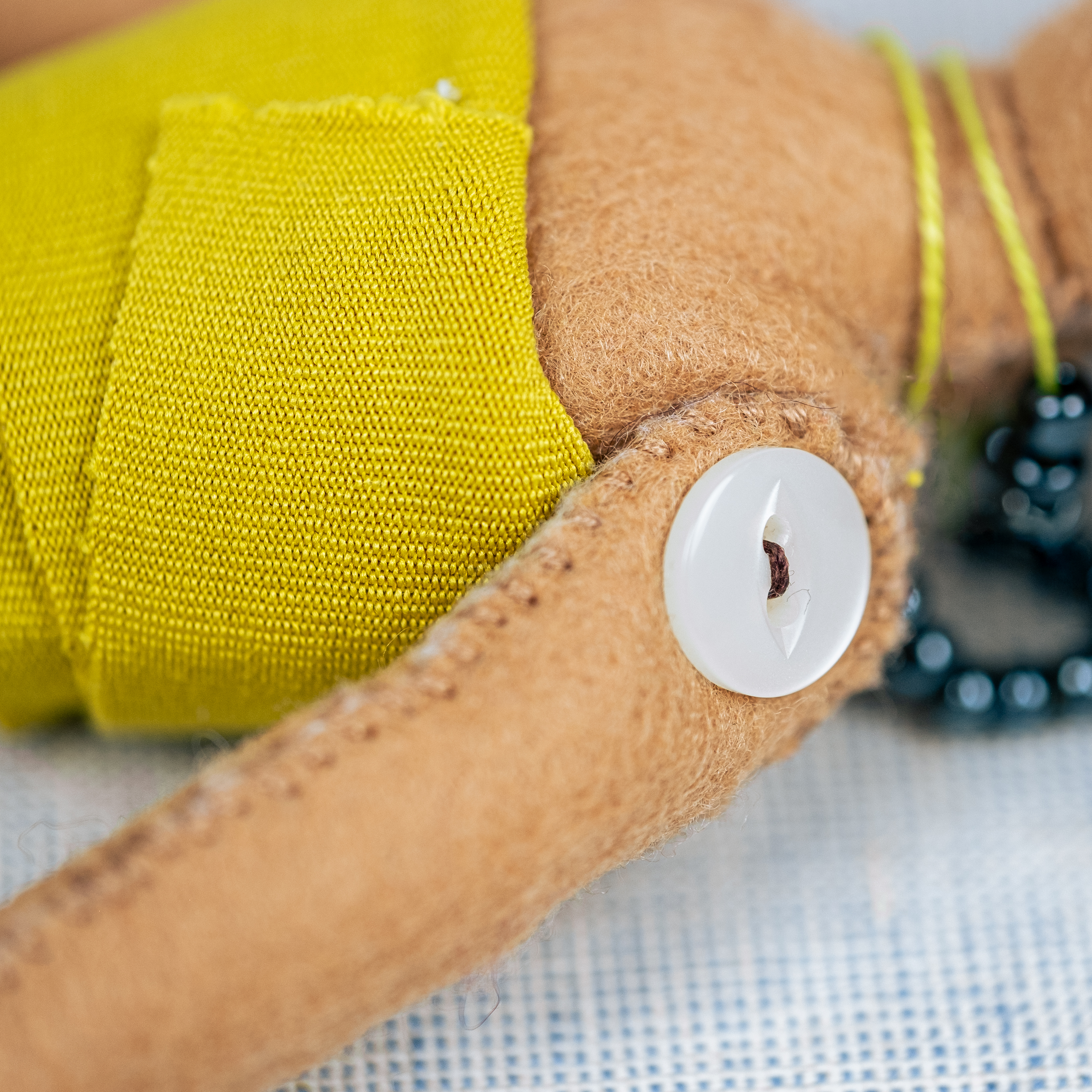 Close up of a yellow fabric doll arm.