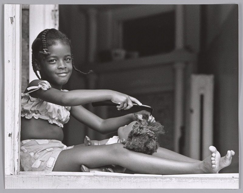 Young girl combing doll's hair.