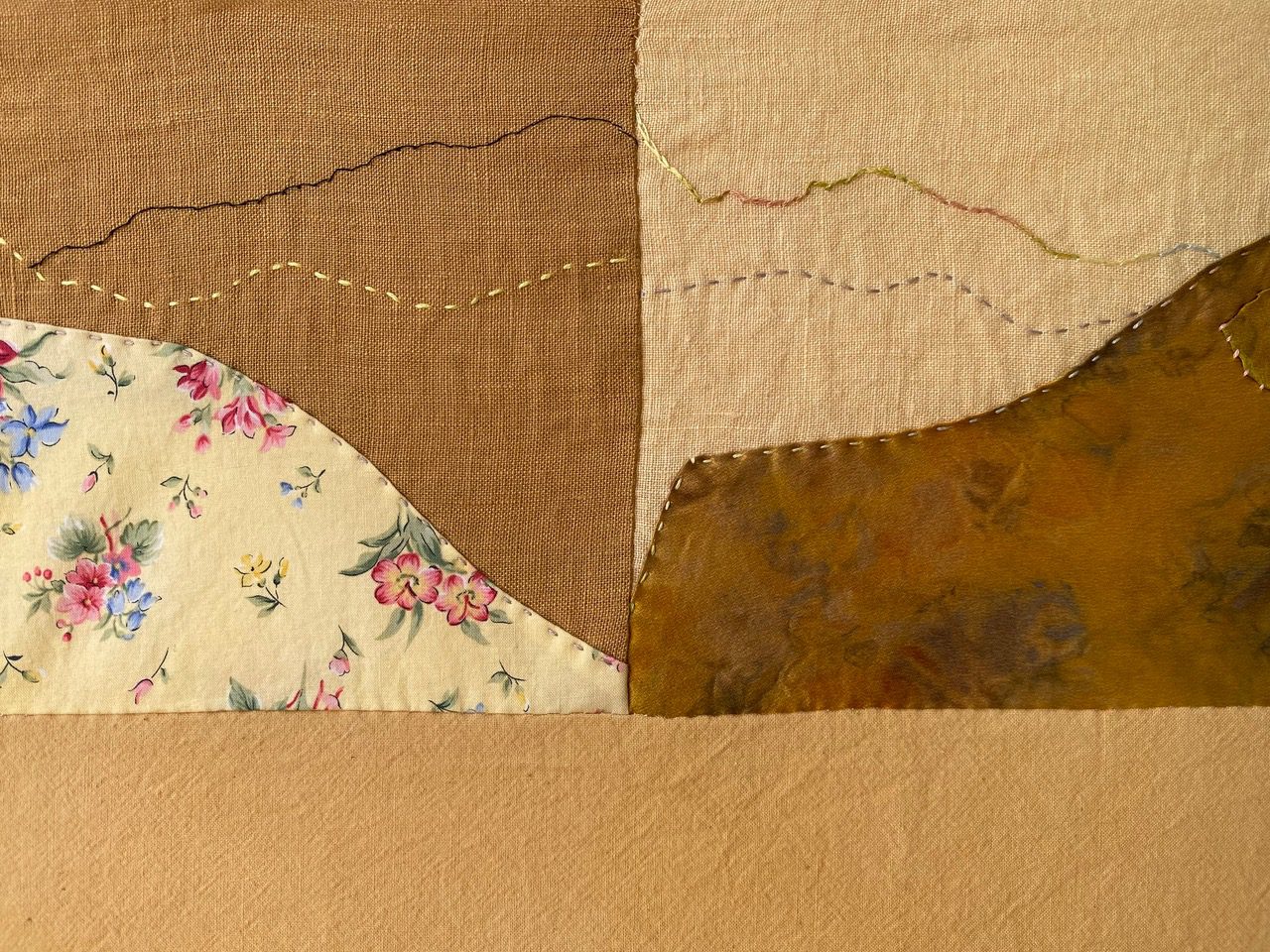 Fabric art with stitched mountain landscape.