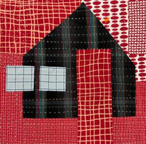 Red and black quilt with a house shape.