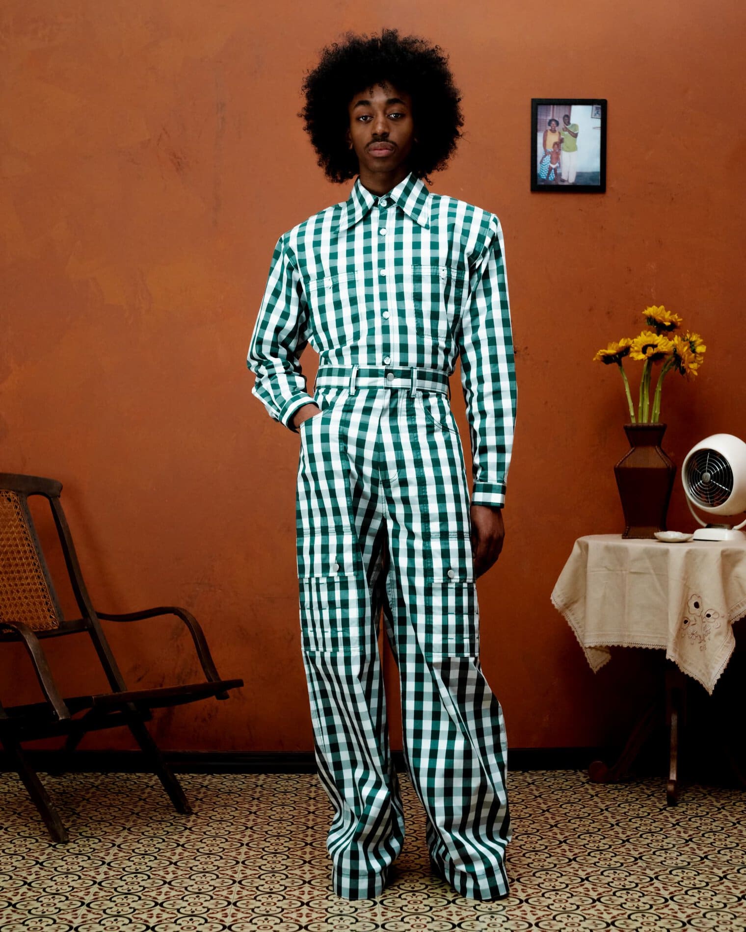 A model poses in a high-waisted jumpsuit of green and white gingham.