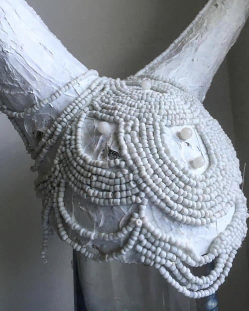 Detail of white beaded embellishments on white horned headpiece.

