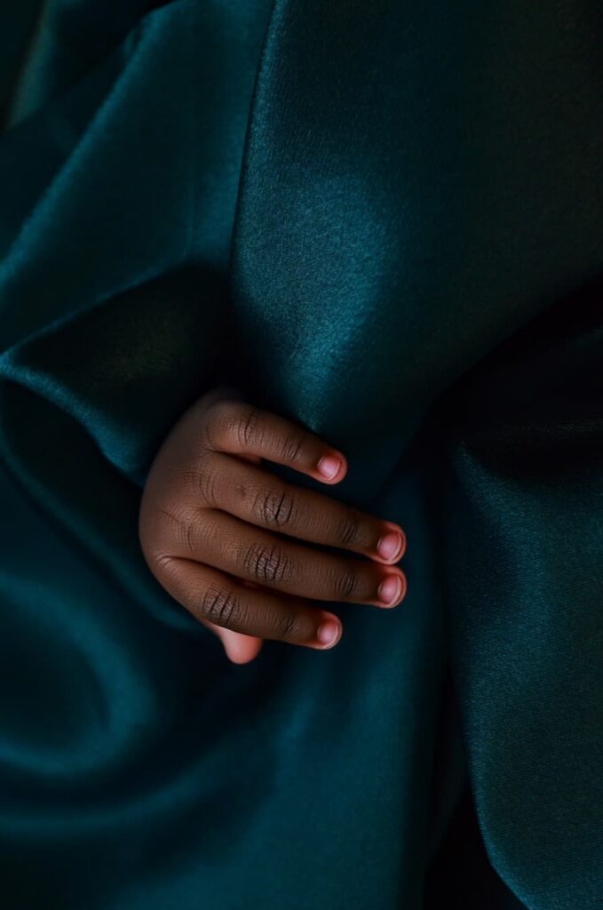 A Black hand surrounded by a silky dark blue fabric.