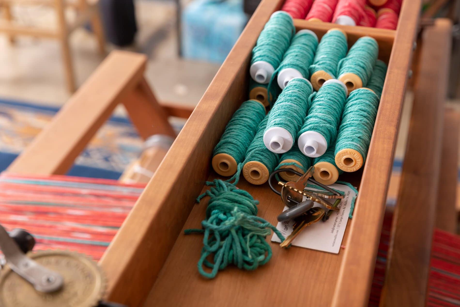 Spools of colored yarn atop a standing loom..
