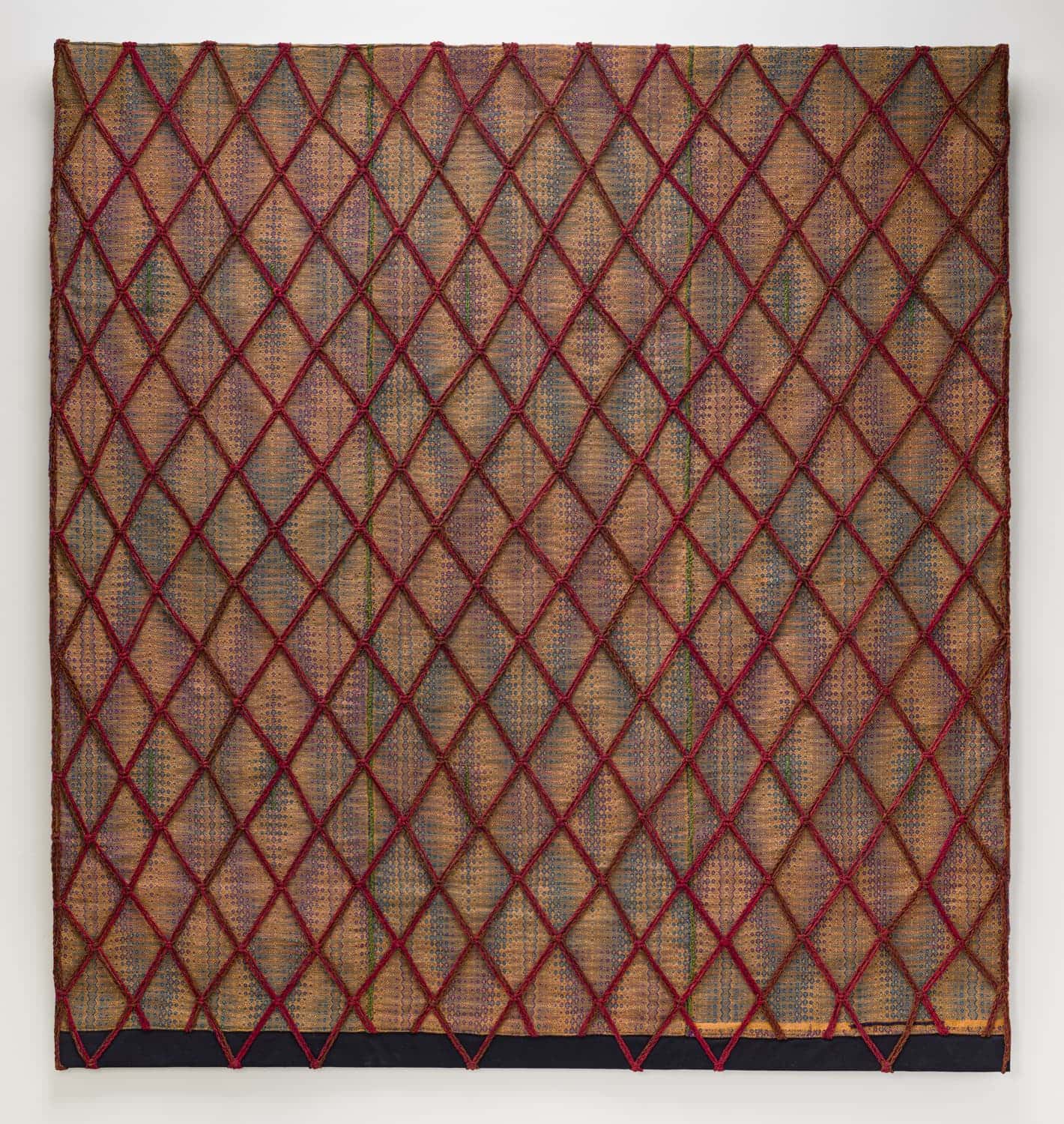 A diamond lattice of red yarns over a handwoven ground of golds, purples, blues and greens. Camille Ann Brewer, EVW.
