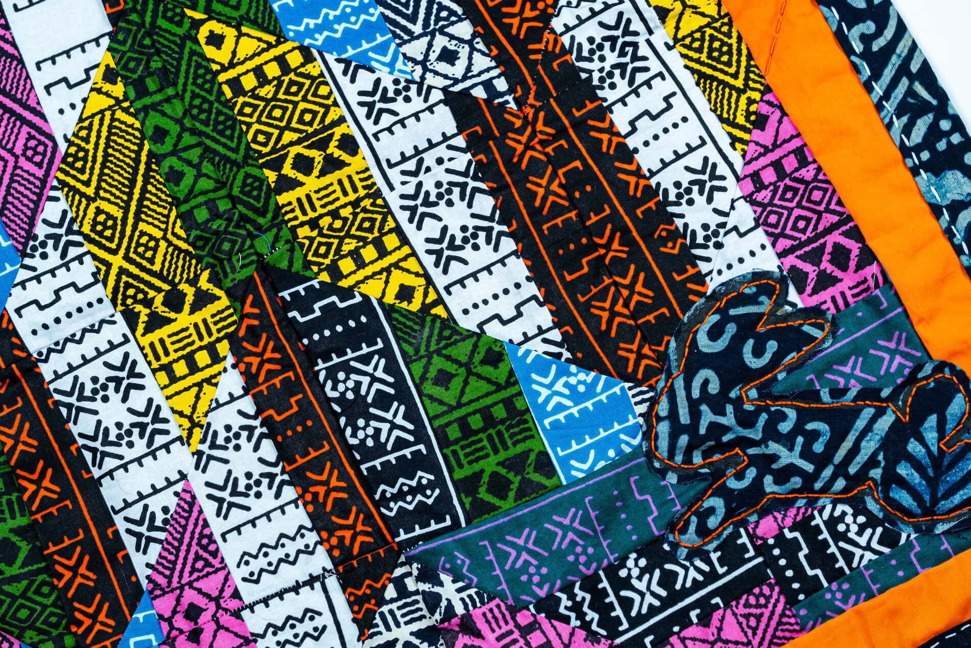 Detail of many patterned fabrics quilted in a stripped chevron pattern.